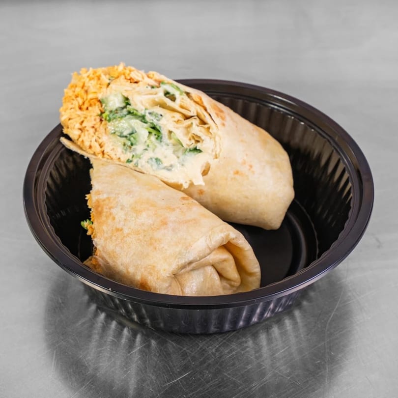Two Burritos & Bowls burritos, one cut open to show the creamy green filling, in a black container.