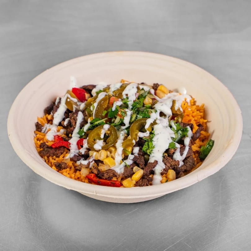 Burritos & Bowls' burrito bowl with rice, meat, corn, peppers, jalapeños, and white sauce.