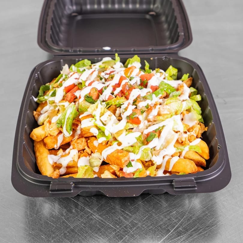 Burritos & Bowls' loaded fries with chicken, lettuce, tomatoes, and white sauce in a black container.